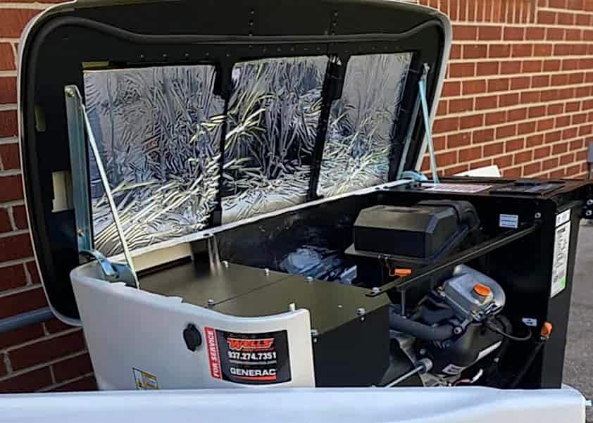 New gen Generac generator with top lifted up against brick wall